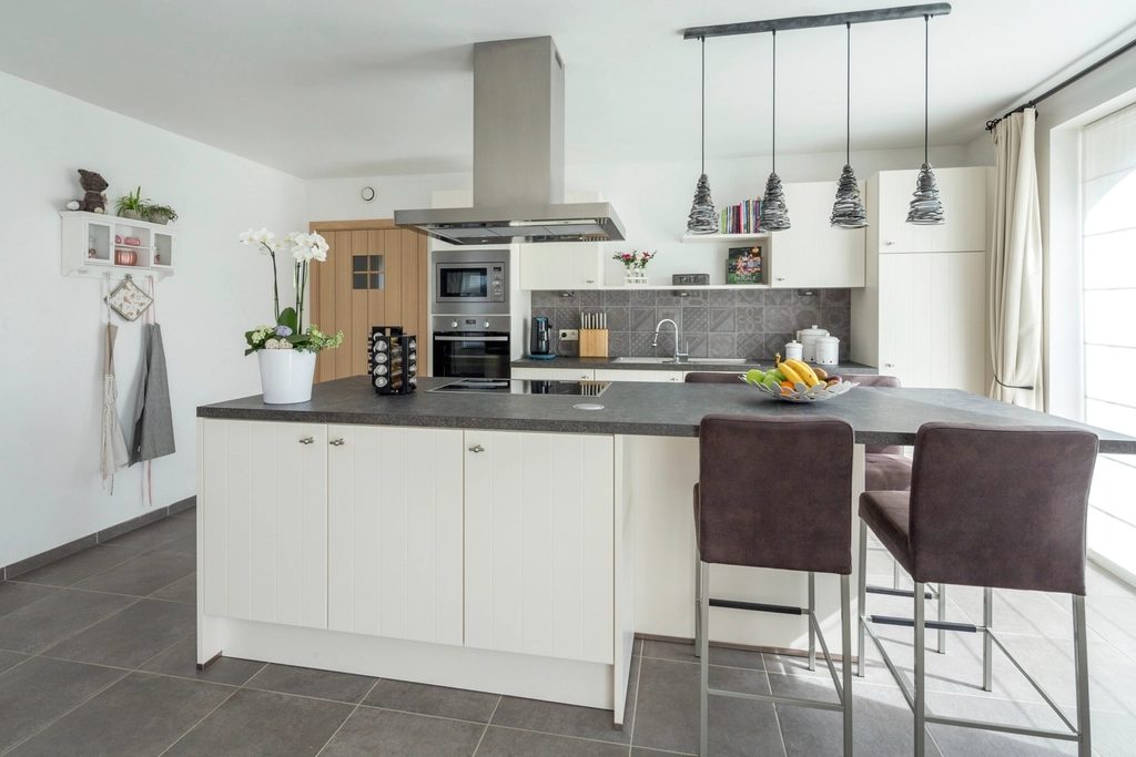 Bright white kitchen with a center island, bar stools, and pendant lights
